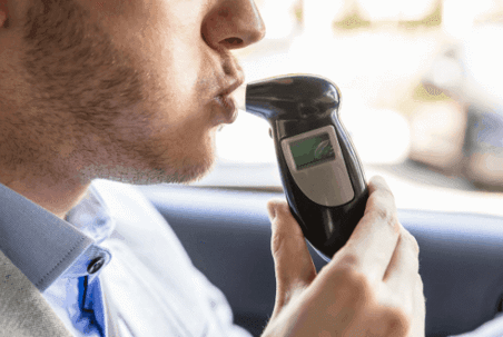 Man breathing into breathalyzer