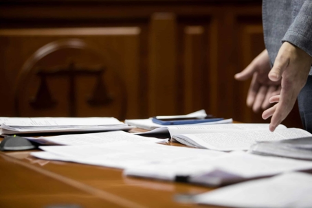 Person standing next to desk with lots of papers on it