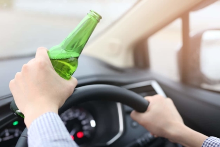 Person driving while holding bottle