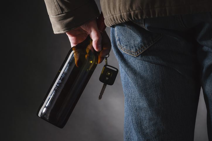 Man Holding Car Keys and Alcohol